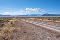 the road is wide and empty in a vast terrain landscape with mountains in the distance