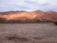 mountains with trees and dry shrubs are shown in the foreground of the desert landscape