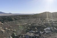 the sun is rising over a barren rocky area with lots of rocks and green grass