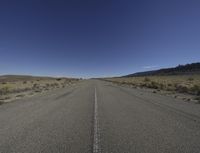 an empty open road with mountains in the background on a sunny day in a remote area