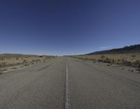an empty open road with mountains in the background on a sunny day in a remote area