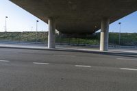 the view from under an overpass on a road in front of the building on the hill