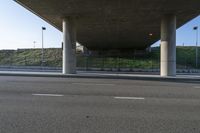 the view from under an overpass on a road in front of the building on the hill