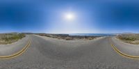 the view looking up at the empty road and ocean in the distance with no trees on either side