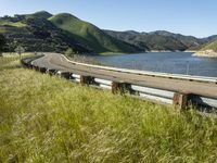 view from the side of a highway with a large body of water and hills in the background