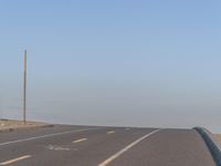 a deserted highway in the desert during day time and the road is empty with yellow stripes