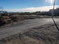 an empty road with dirt on it, leading into the distance, and another road in the foreground