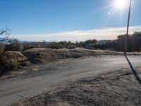 an empty road with dirt on it, leading into the distance, and another road in the foreground