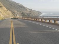 a view of the ocean from the side of a road near a coastline, with a photographer in the distance taking pictures