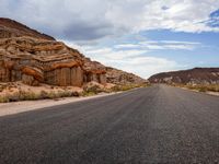 a highway is lined with rock and desert formations, with a car driving down the road