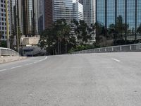 a person rides a skateboard on an empty road in the middle of city buildings