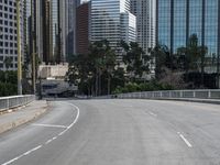 a person rides a skateboard on an empty road in the middle of city buildings