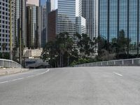 a person rides a skateboard on an empty road in the middle of city buildings