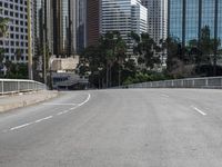 a person rides a skateboard on an empty road in the middle of city buildings