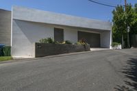 the road outside of the house is empty, with a curb and garden in the front