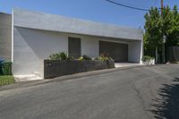 the road outside of the house is empty, with a curb and garden in the front