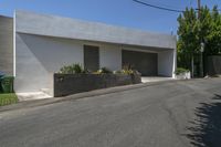 the road outside of the house is empty, with a curb and garden in the front