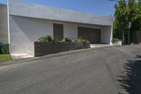 the road outside of the house is empty, with a curb and garden in the front