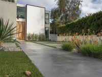 front entrance, driveway and large home in hollywood angeles with large green bushes, stone path, trees and shrubs