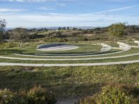 an empty circular park and paved street with benches in it that are made of stone