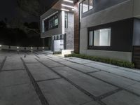 a modern villa with night lighting and an outdoor staircase and courtyard area is seen here