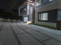 a modern villa with night lighting and an outdoor staircase and courtyard area is seen here