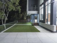 an open courtyard with artificial grass and steps next to it in front of the house