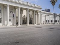 this is a large building with columns on the front and sides of it and palm trees