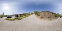 a 360 - angle panorama of a gravel driveway and house on top of a hill