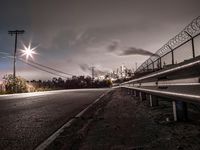 a deserted street is at the edge of an industrial area at night with the sky showing,