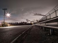 a deserted street is at the edge of an industrial area at night with the sky showing,