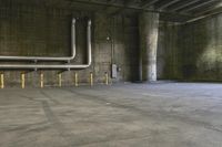 an empty industrial space with a bunch of pipes, benches and a parking lot inside