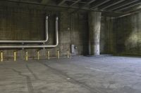 an empty industrial space with a bunch of pipes, benches and a parking lot inside