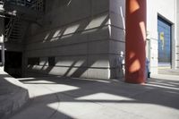 a fire hydrant near a tall pillar and stairs outside a building that has a red pillar in the background