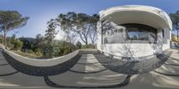 the circular shaped building overlooks trees and a trail of shadows, while people in white jackets stand on the walkway