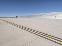 the runway is paved with yellow lines leading into the building, a man walking towards it