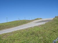 a person riding a motorcycle on a winding hill with barbed fence and blue sky in the background