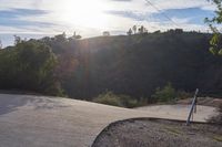 the sun is setting behind a hill behind a stop sign with a large rock face