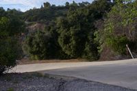 the sun is setting behind a hill behind a stop sign with a large rock face