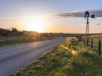 a country road at sunset with an old fashioned windmill in the distance, photographed in rural areas