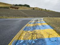 this is a yellow and blue painted line along the road in front of a hillside