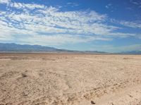 a man sitting on the ground in the desert while looking at the camera with no one around him