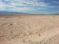 a man sitting on the ground in the desert while looking at the camera with no one around him