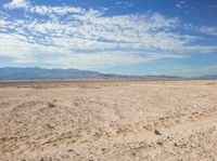 a man sitting on the ground in the desert while looking at the camera with no one around him