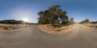 a fish eye lens is showing an empty road with a sun in the background that appears to be in the center of it