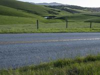 a motorcycle is parked at the side of a road in the grass area of a large valley