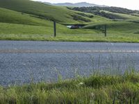 a motorcycle is parked at the side of a road in the grass area of a large valley