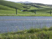 a motorcycle is parked at the side of a road in the grass area of a large valley