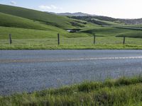 a motorcycle is parked at the side of a road in the grass area of a large valley