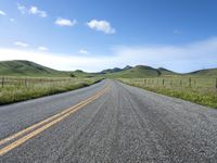 a road that has lines in the middle and mountains on both sides behind it, and blue skies above the horizon